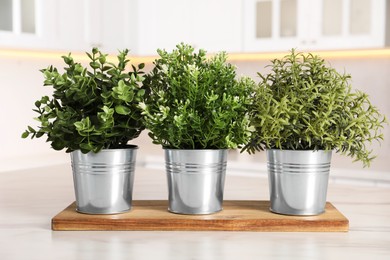 Photo of Artificial potted herbs on white marble table in kitchen. Home decor