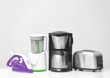 Photo of Household and kitchen appliances on table against light background. Interior element