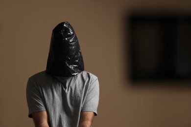 Photo of Man wrapped in black plastic bag on his head against dark background. Hostage taking