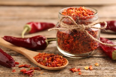 Photo of Chili pepper flakes and pods on wooden table, closeup