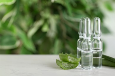 Pharmaceutical ampoules with medication and aloe leaves on white table, closeup. Space for text