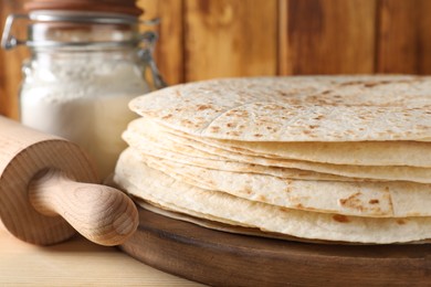 Photo of Many tasty homemade tortillas on wooden table, closeup