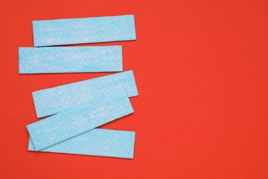 Photo of Sticks of tasty chewing gum on red background, flat lay. Space for text