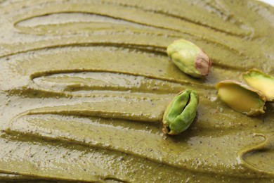 Photo of Fresh pistachio nuts on tasty cream, closeup view