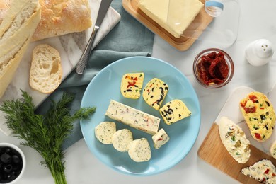 Photo of Different types of tasty butter served on white marble table, flat lay