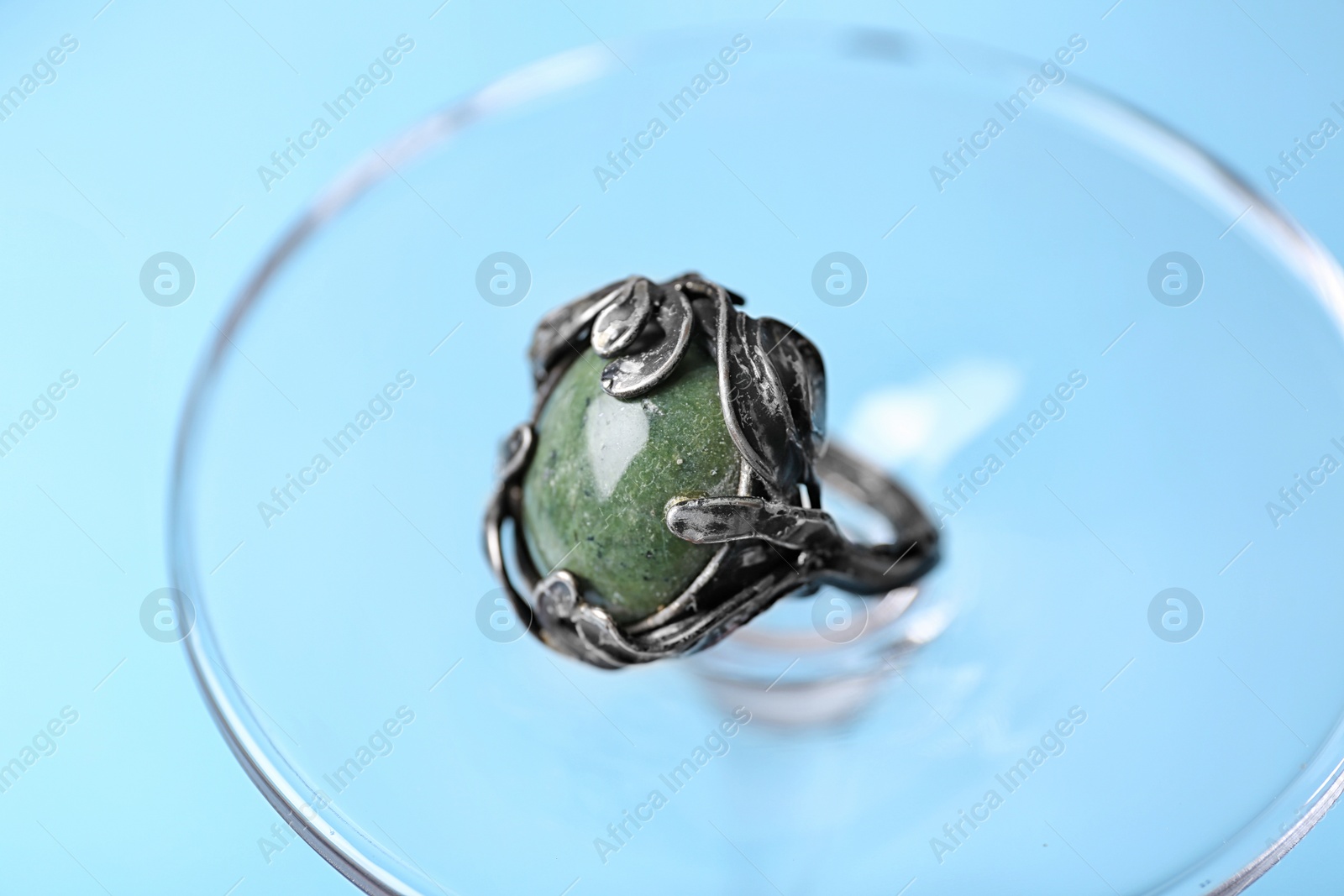 Photo of Beautiful silver ring with opal gemstone on light blue background, closeup
