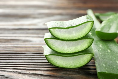 Photo of Fresh aloe vera pieces on wooden table, closeup. Space for text