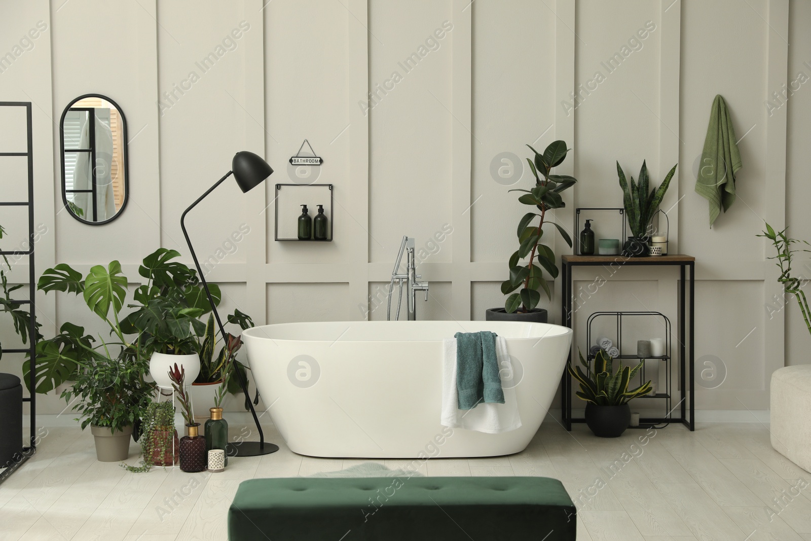 Photo of Stylish bathroom interior with modern tub and beautiful houseplants. Home design