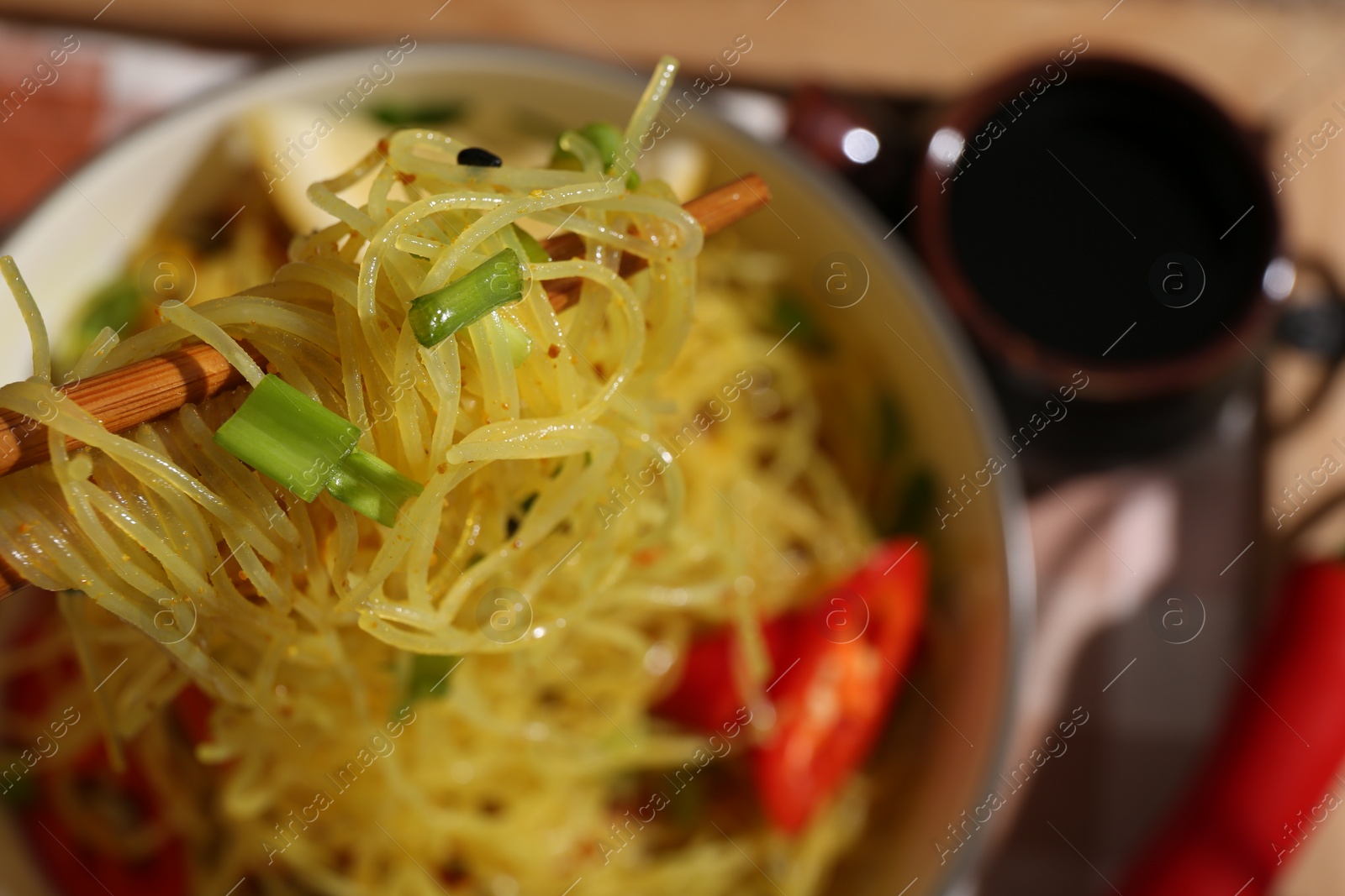 Photo of Stir-fry. Eating tasty noodles with chopsticks at table, closeup and space for text