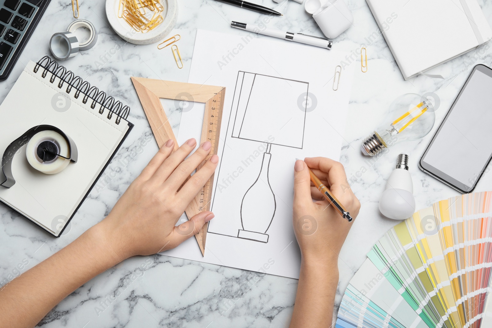 Photo of Designer drawing lamp at white marble table, top view