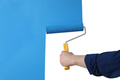 Man applying light blue paint with roller brush on white wall, closeup