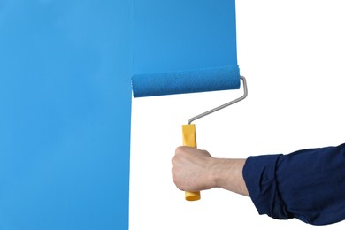 Photo of Man applying light blue paint with roller brush on white wall, closeup