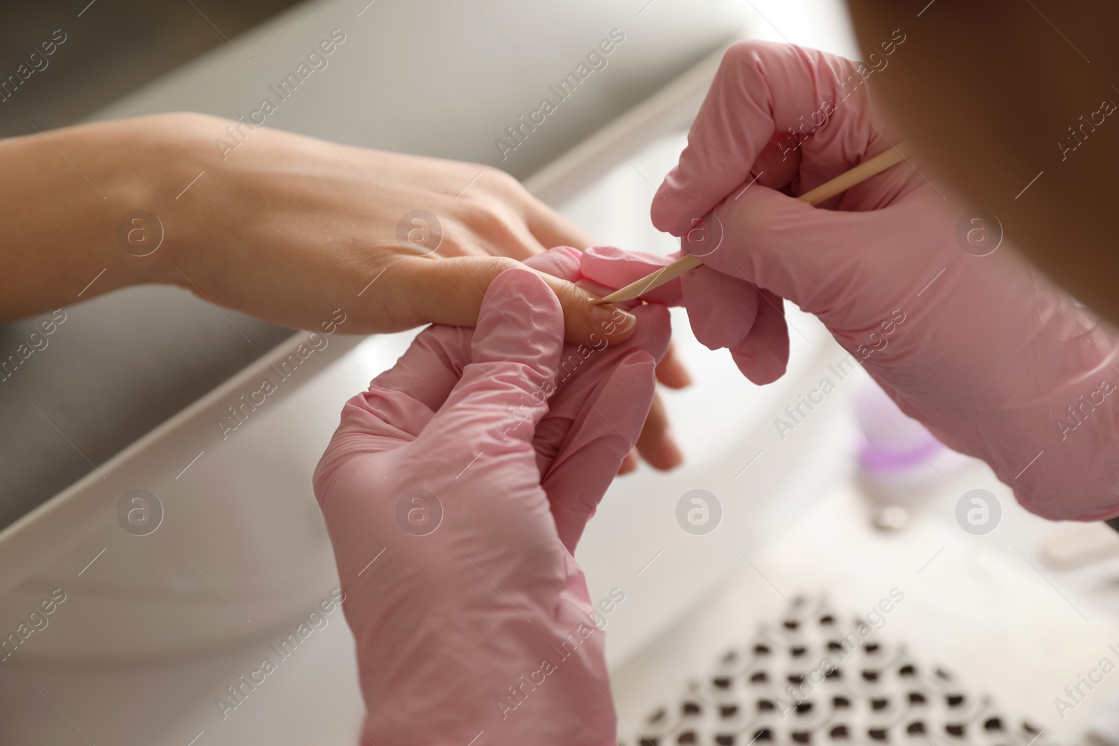 Photo of Professional manicurist working with client in beauty salon, closeup