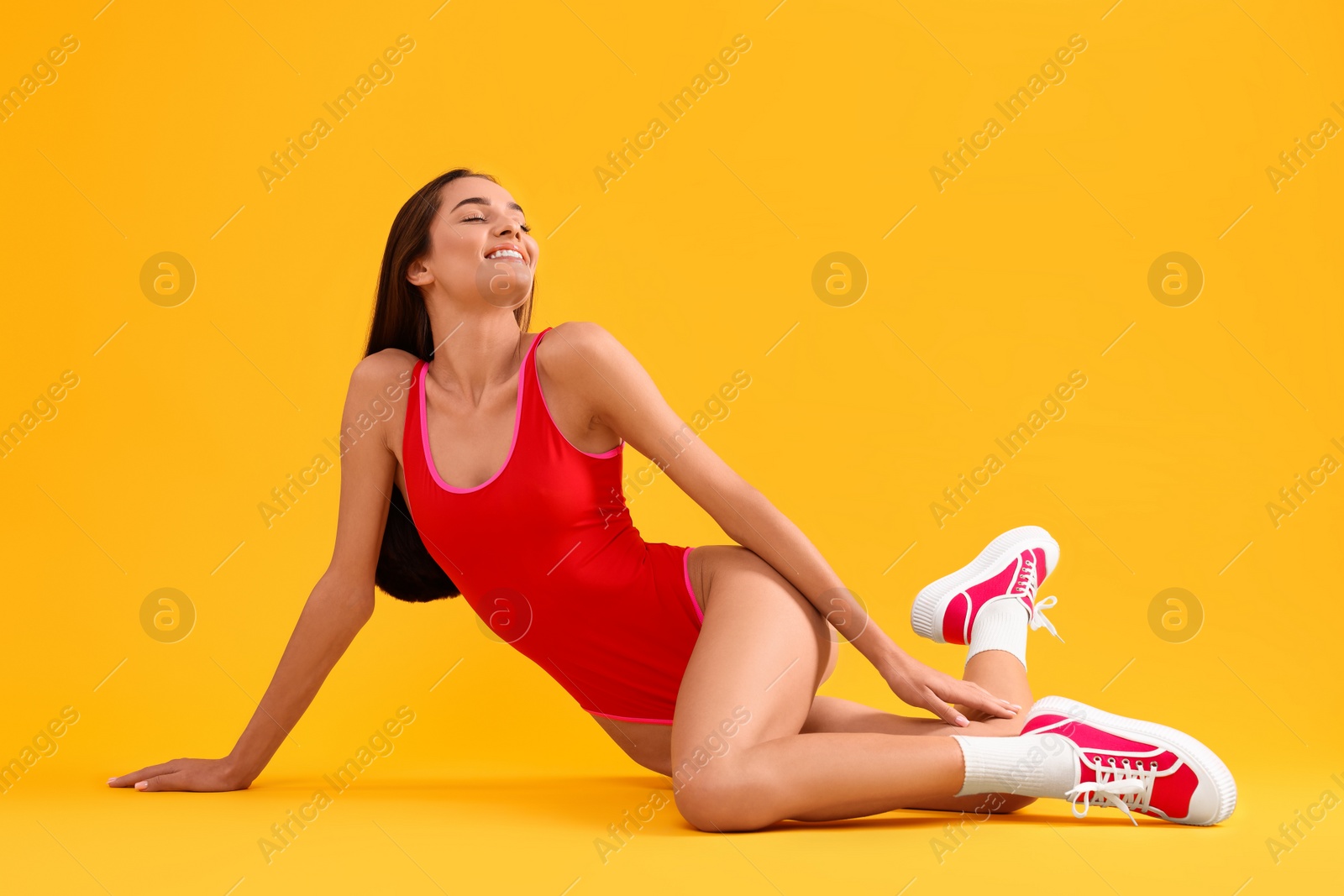 Photo of Young woman in stylish swimsuit on yellow background