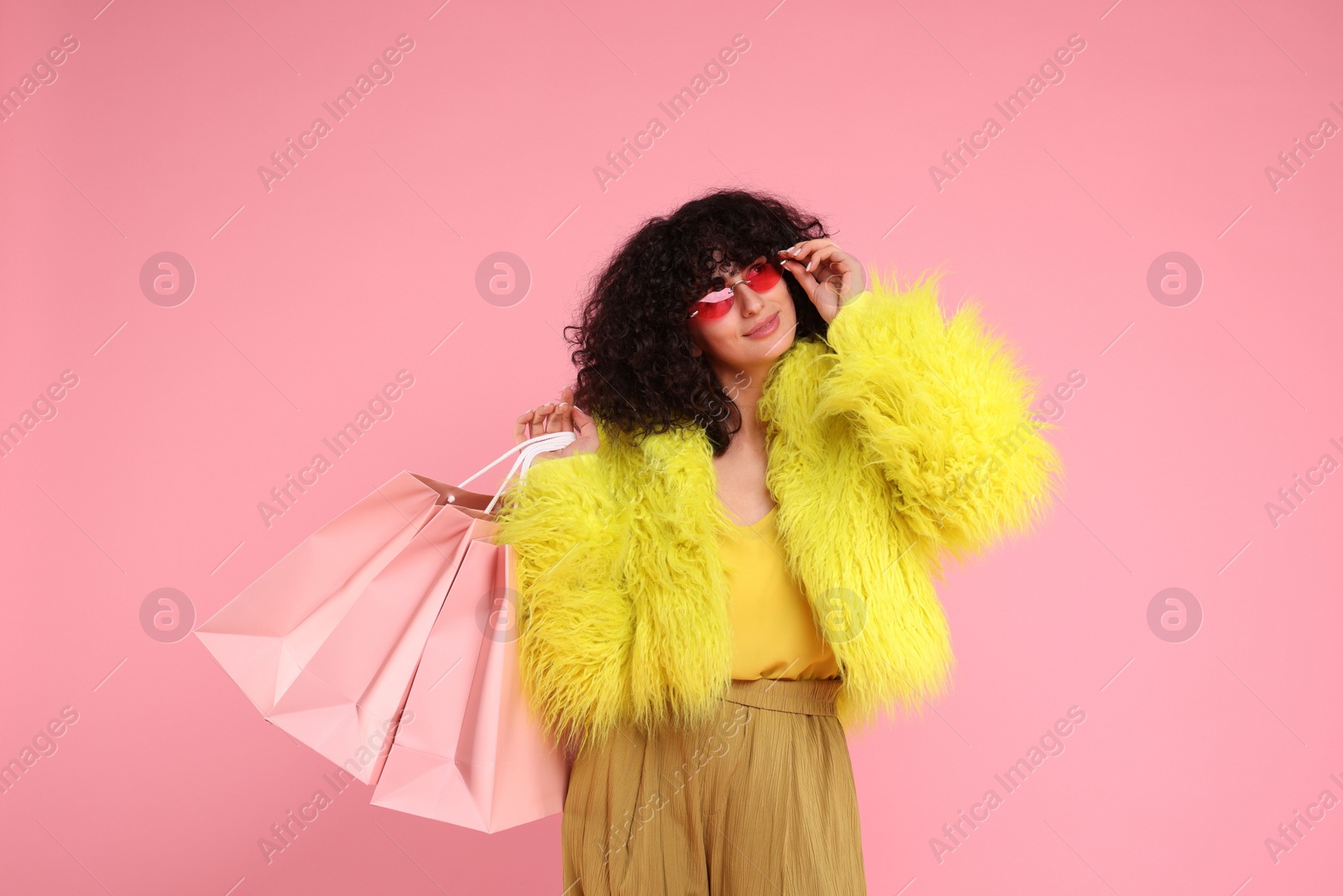 Photo of Happy young woman with shopping bags on pink background