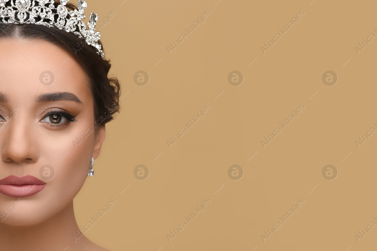 Photo of Beautiful young woman wearing luxurious tiara on beige background, closeup. Space for text