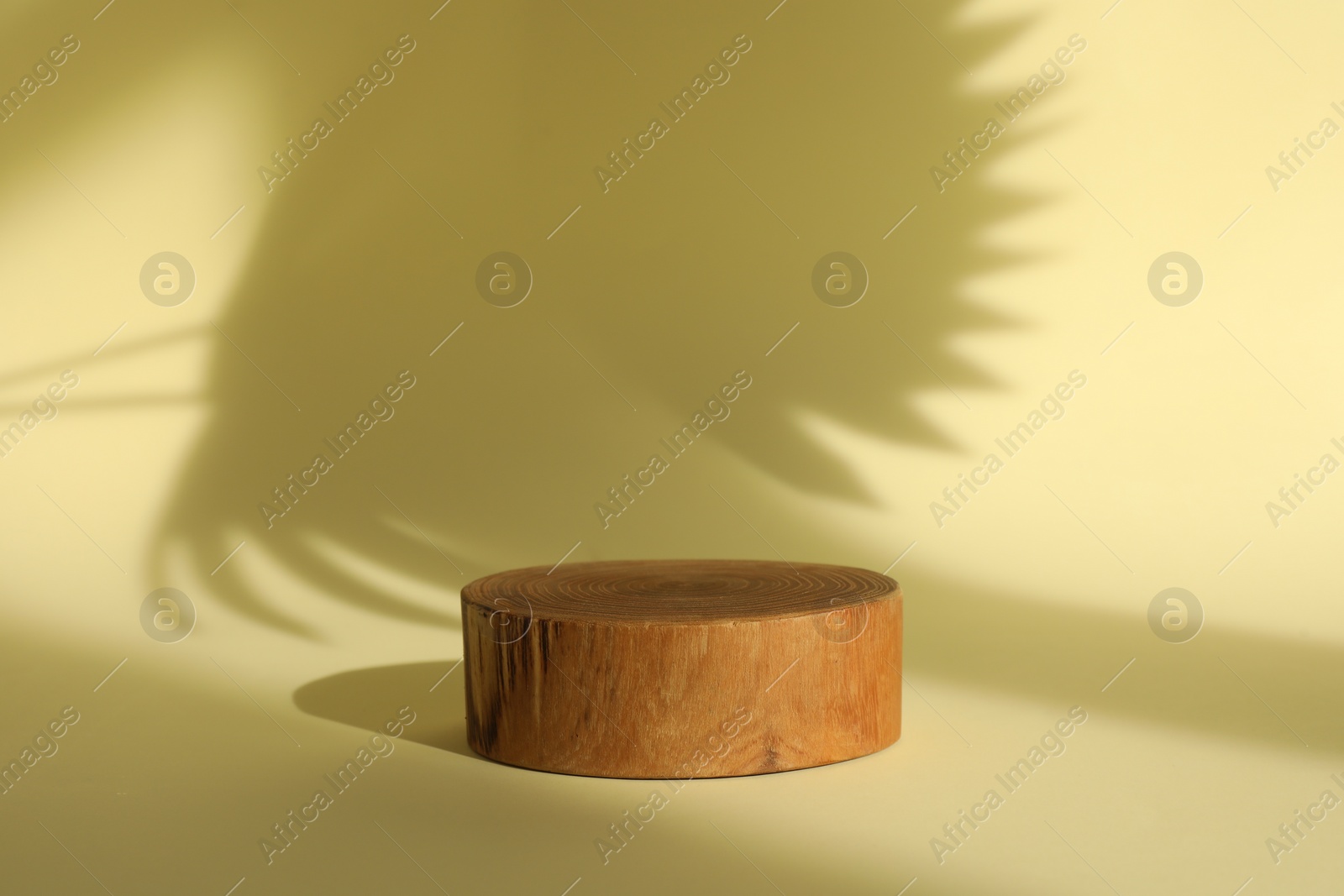 Photo of Presentation of product. Wooden podium on yellow background. Space for text