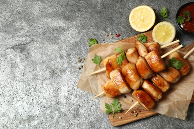 Delicious chicken shish kebabs with parsley and lemon on grey table, flat lay. Space for text
