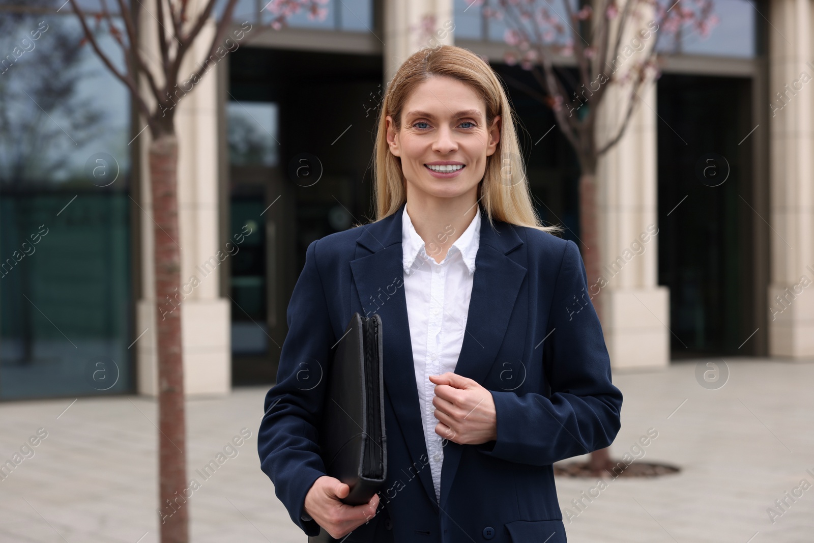 Photo of Female real estate agent with leather portfolio outdoors