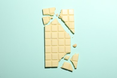 Delicious white chocolate on turquoise background, top view