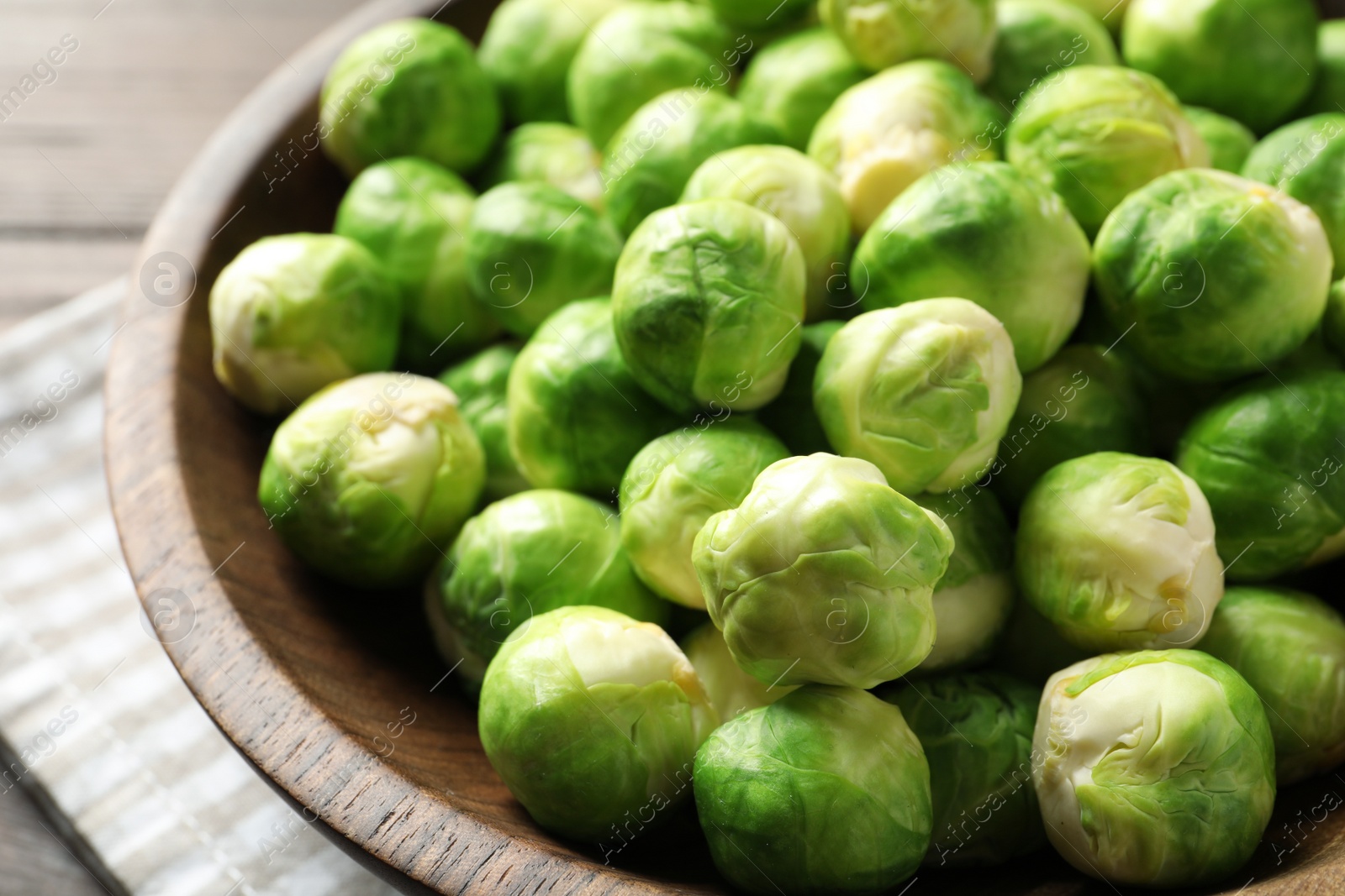 Photo of Fresh Brussels sprouts in bowl on table, closeup