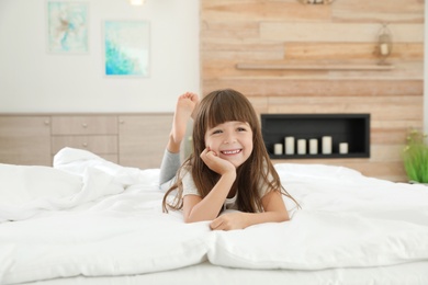 Photo of Cute little girl lying on bed at home