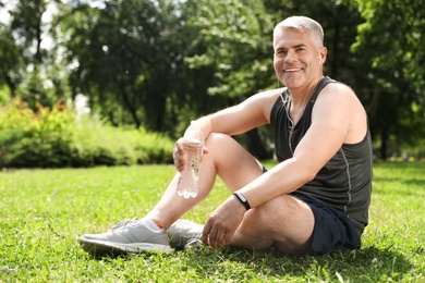 Photo of Handsome mature man having rest after exercise in park. Healthy lifestyle