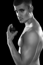 Photo of Handsome young man with bottle of perfume, black and white effect