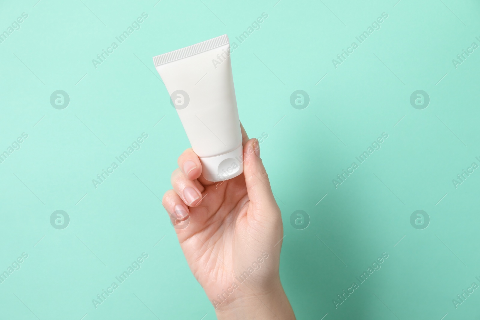 Photo of Woman with tube of hand cream on turquoise background, closeup