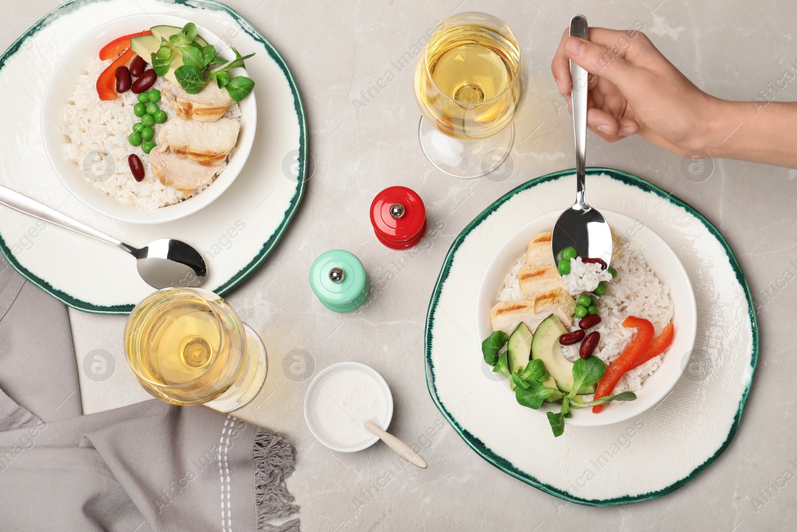 Photo of Woman eating boiled rice with vegetables and meat at table, top view