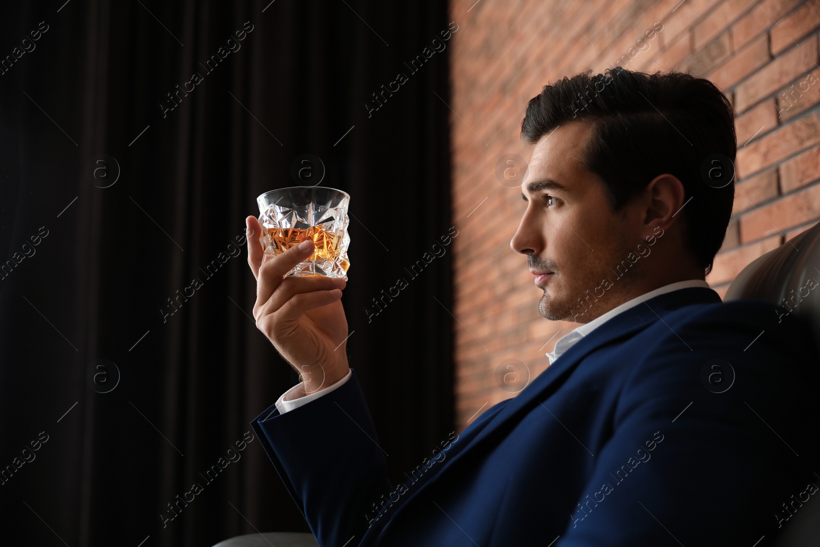 Photo of Young man with glass of whiskey indoors