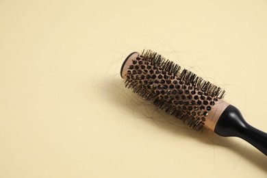 Photo of Professional brush with lost hair on beige background, closeup. Space for text