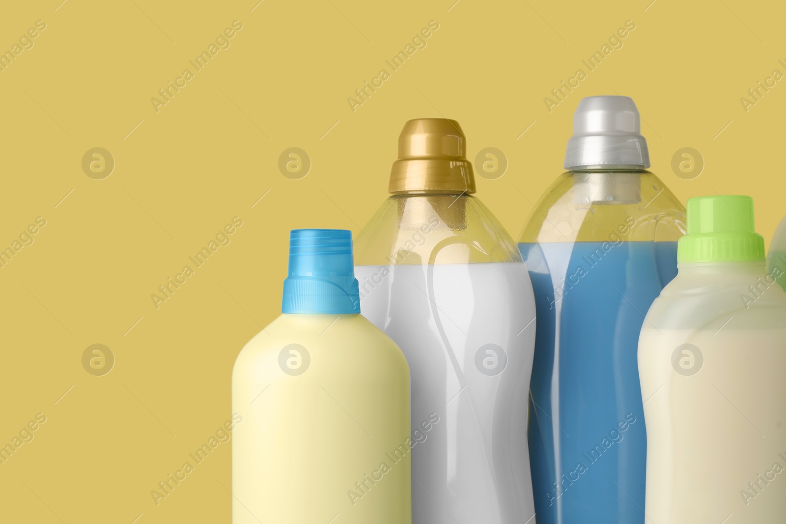 Photo of Bottles of fabric softener on yellow background, space for text