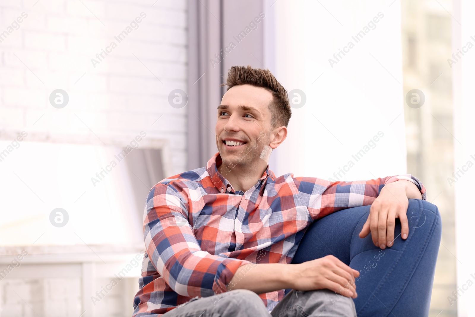 Photo of Young man sitting in armchair at home