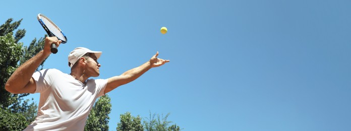 Man playing tennis on sunny day, low angle view. Banner design with space for text