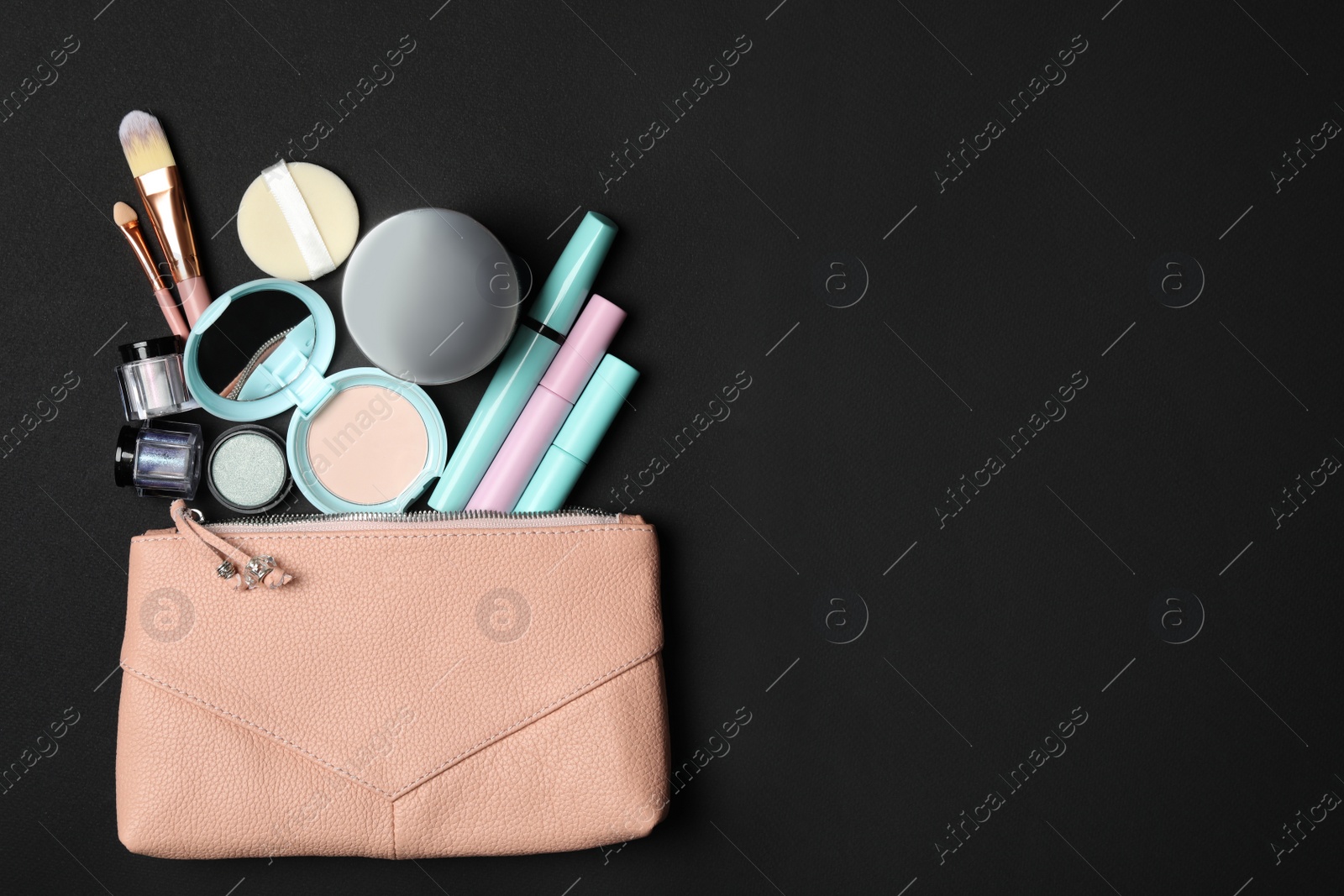 Photo of Cosmetic bag with makeup products and beauty accessories on black background, flat lay. Space for text