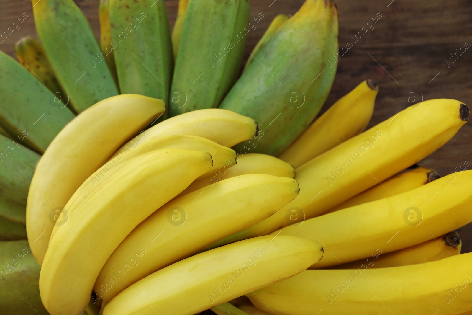 Photo of Bunches of tasty bananas on wooden table, closeup