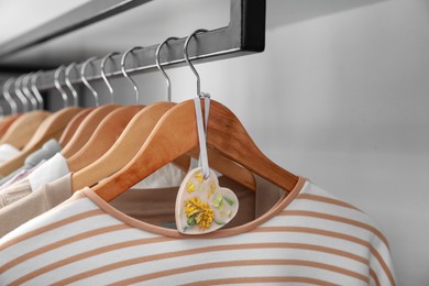 Photo of Beautiful scented sachet and clothes hanging in wardrobe