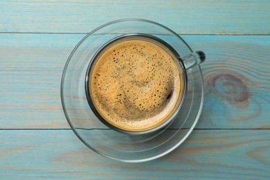 Photo of Cup of aromatic coffee on light blue wooden table, top view