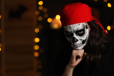 Photo of Man in scary pirate costume with skull makeup against blurred lights indoors, space for text. Halloween celebration