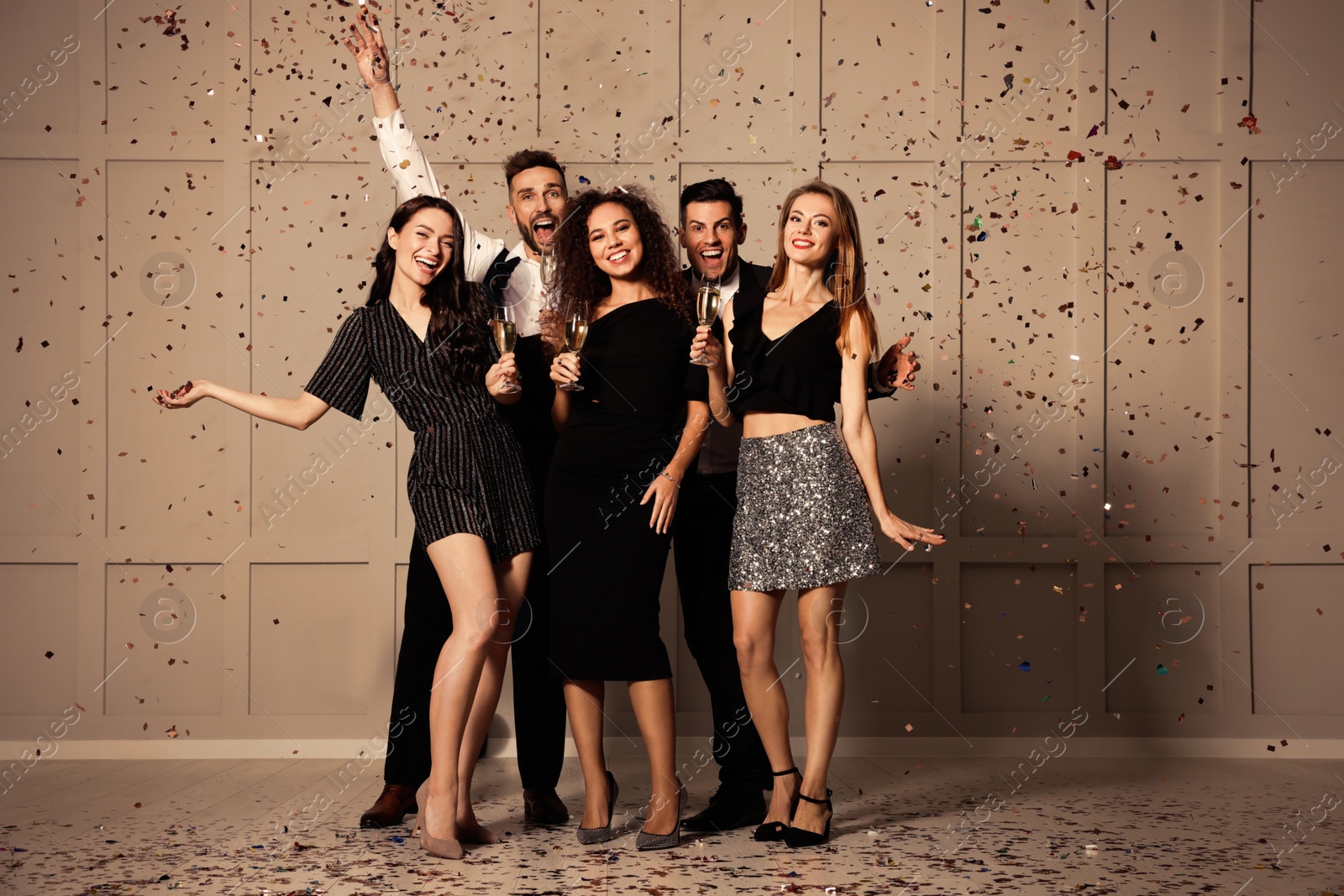 Photo of Happy friends with glasses of sparkling wine celebrating New Year indoors