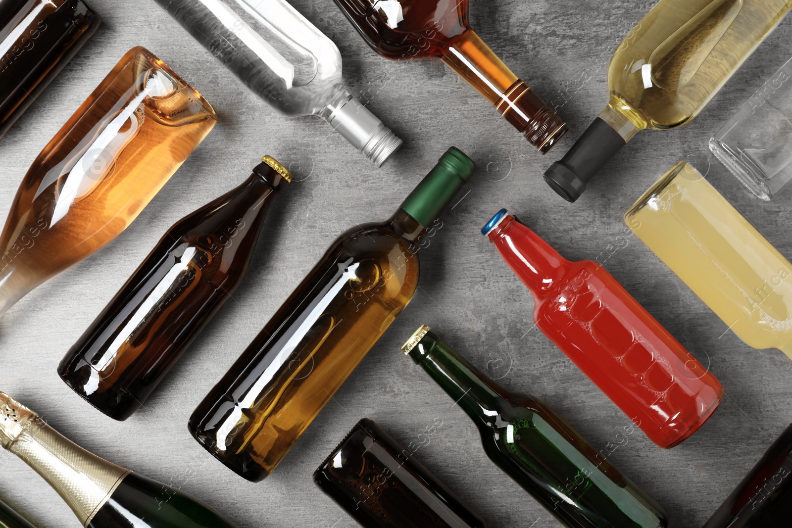 Photo of Bottles with different alcoholic drinks on grey background, flat lay