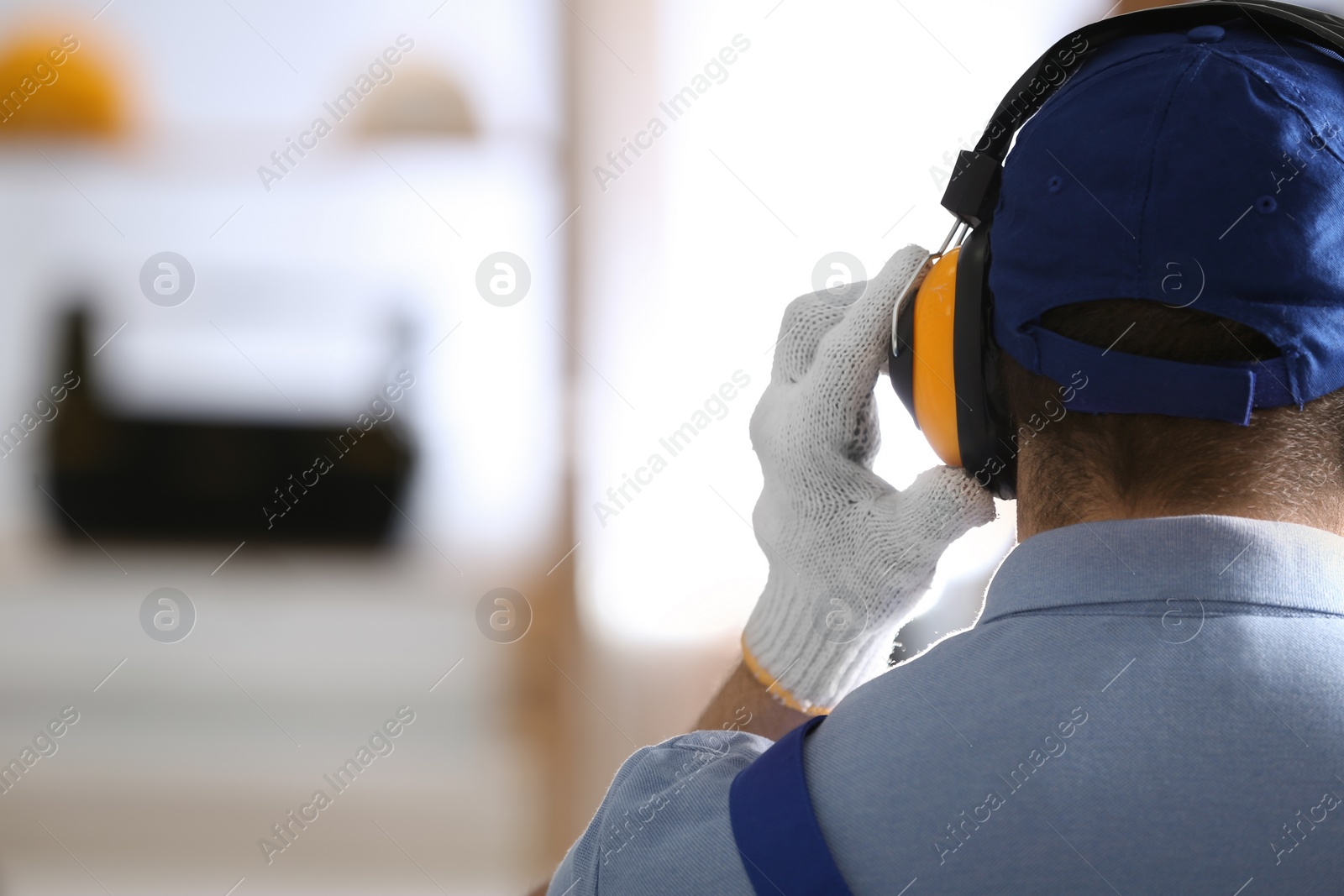 Photo of Worker wearing safety headphones indoors, back view with space for text. Hearing protection device