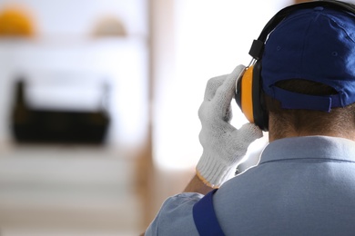 Photo of Worker wearing safety headphones indoors, back view with space for text. Hearing protection device