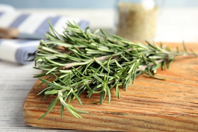 Photo of Wooden board with fresh rosemary twigs on table