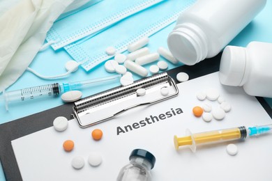 Photo of Composition of clipboard with word Anesthesia and drugs on light blue background, closeup