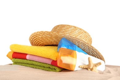 Beach accessories on sand against white background