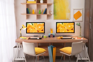 Modern workplace with large desk and computers in room. Stylish interior