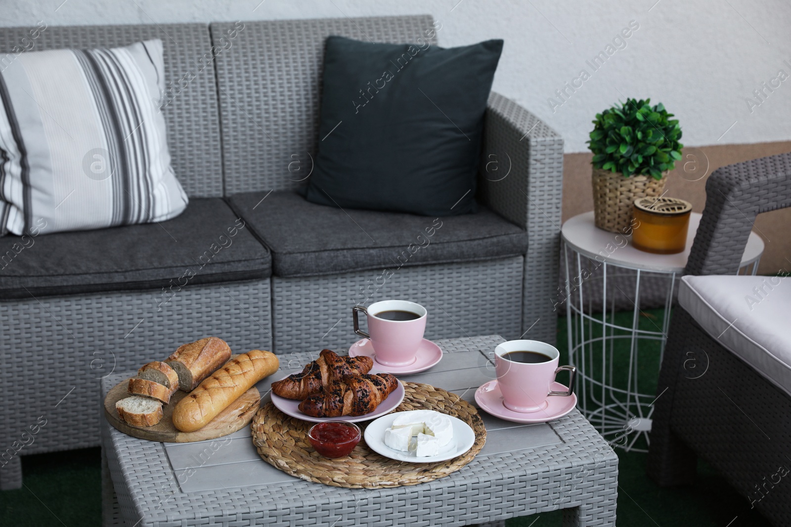 Outdoor breakfast with tea and croissants on rattan table on terrace Photo of Outdoor breakfast with tea and croissants on rattan table on terrace