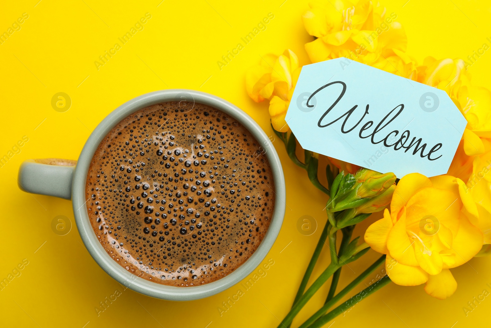 Image of Welcome card, beautiful freesia flowers and cup of aromatic coffee on yellow background, flat lay